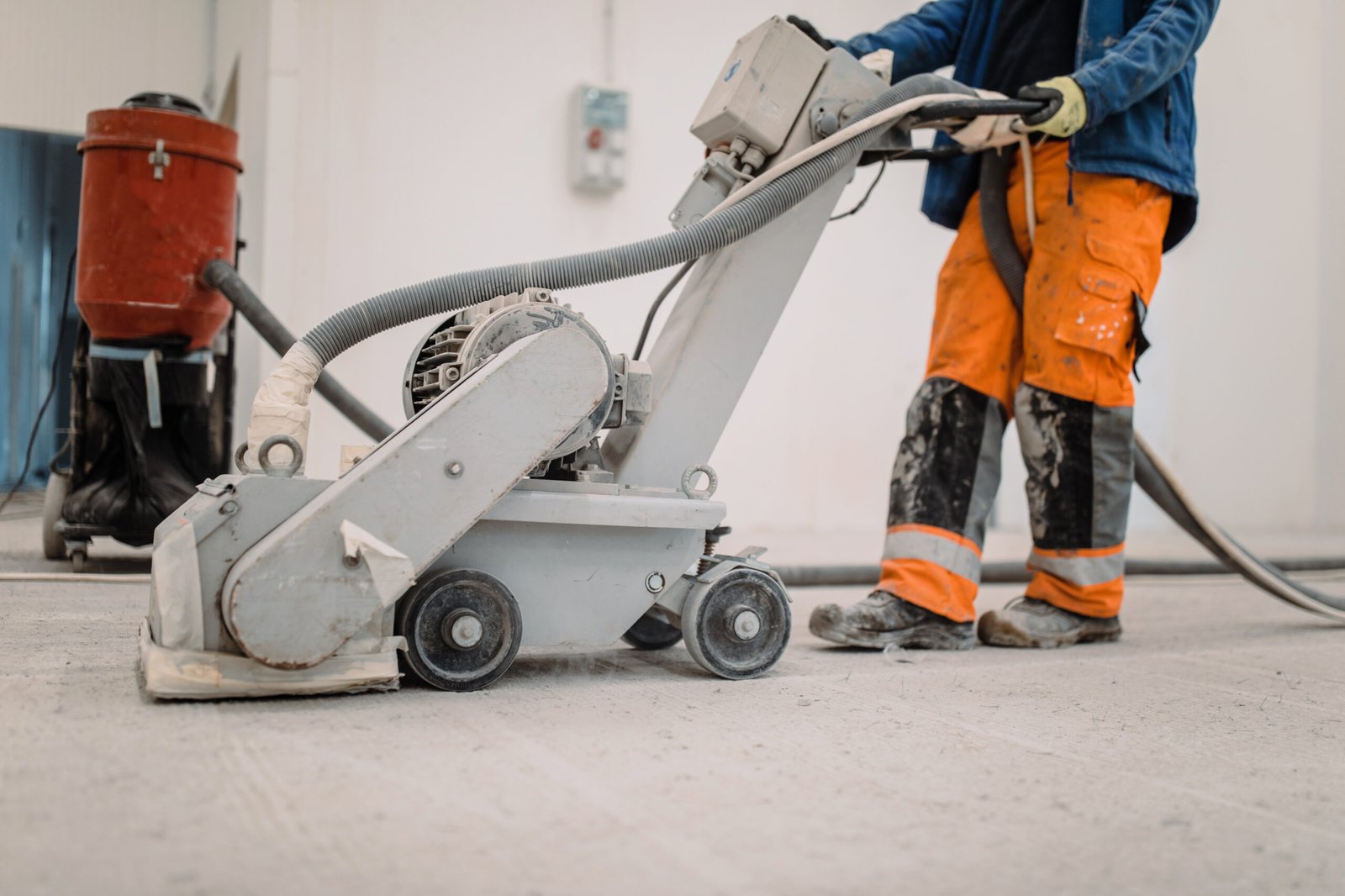 Workers grind the concrete floor at the construction site. Workers grind the concrete floor at the construction site. Prepares the floor for polyurethane mortar